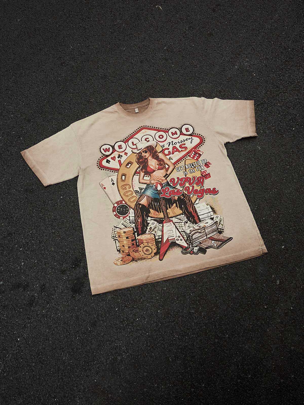 A high-angle flat lay of the Las Vegas Girl T-shirt on a white background, showing the full graphic and the brand's neck label.