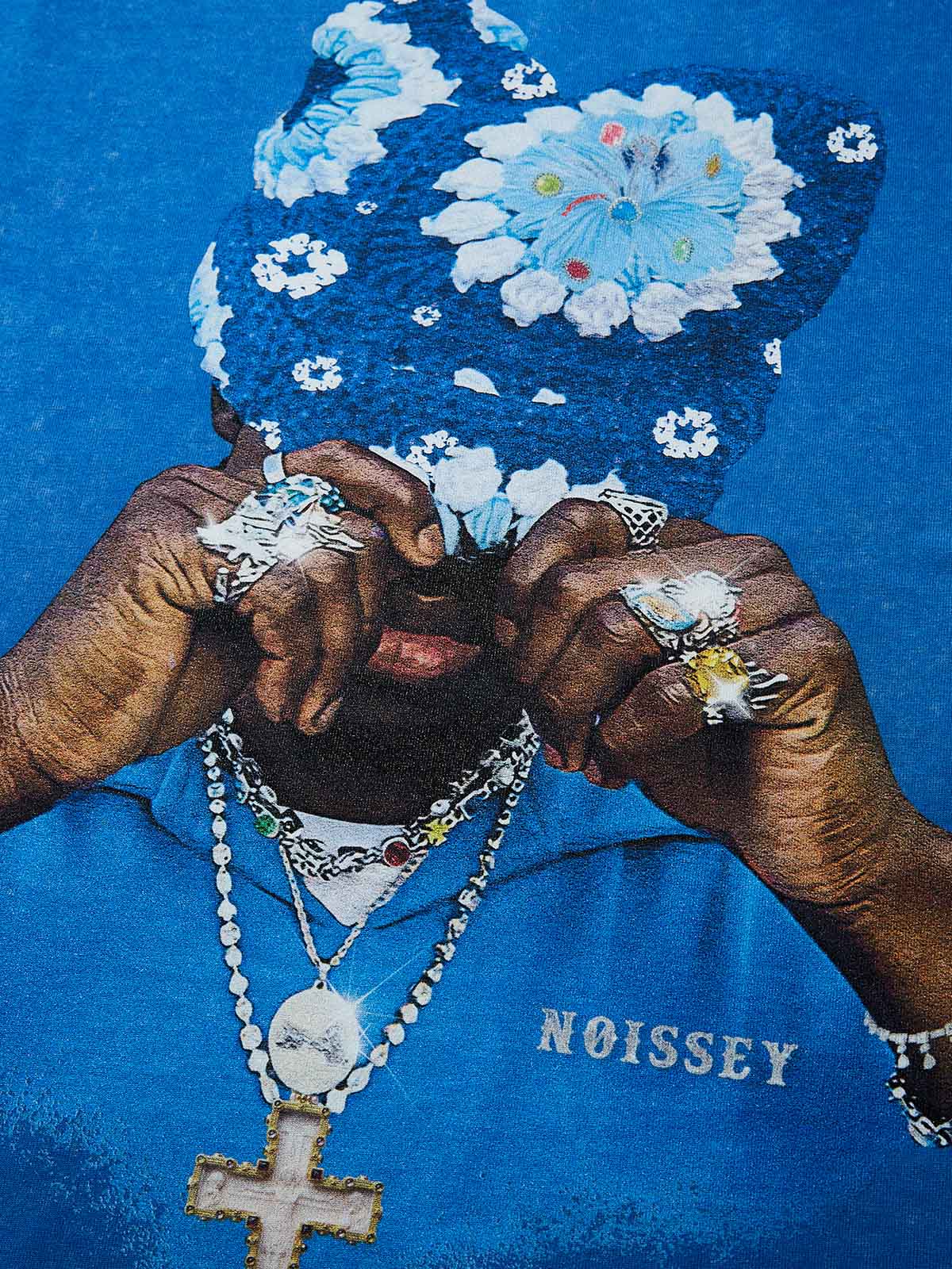 Close-up of graphic print showing a man covering face with a blue floral knit beanie