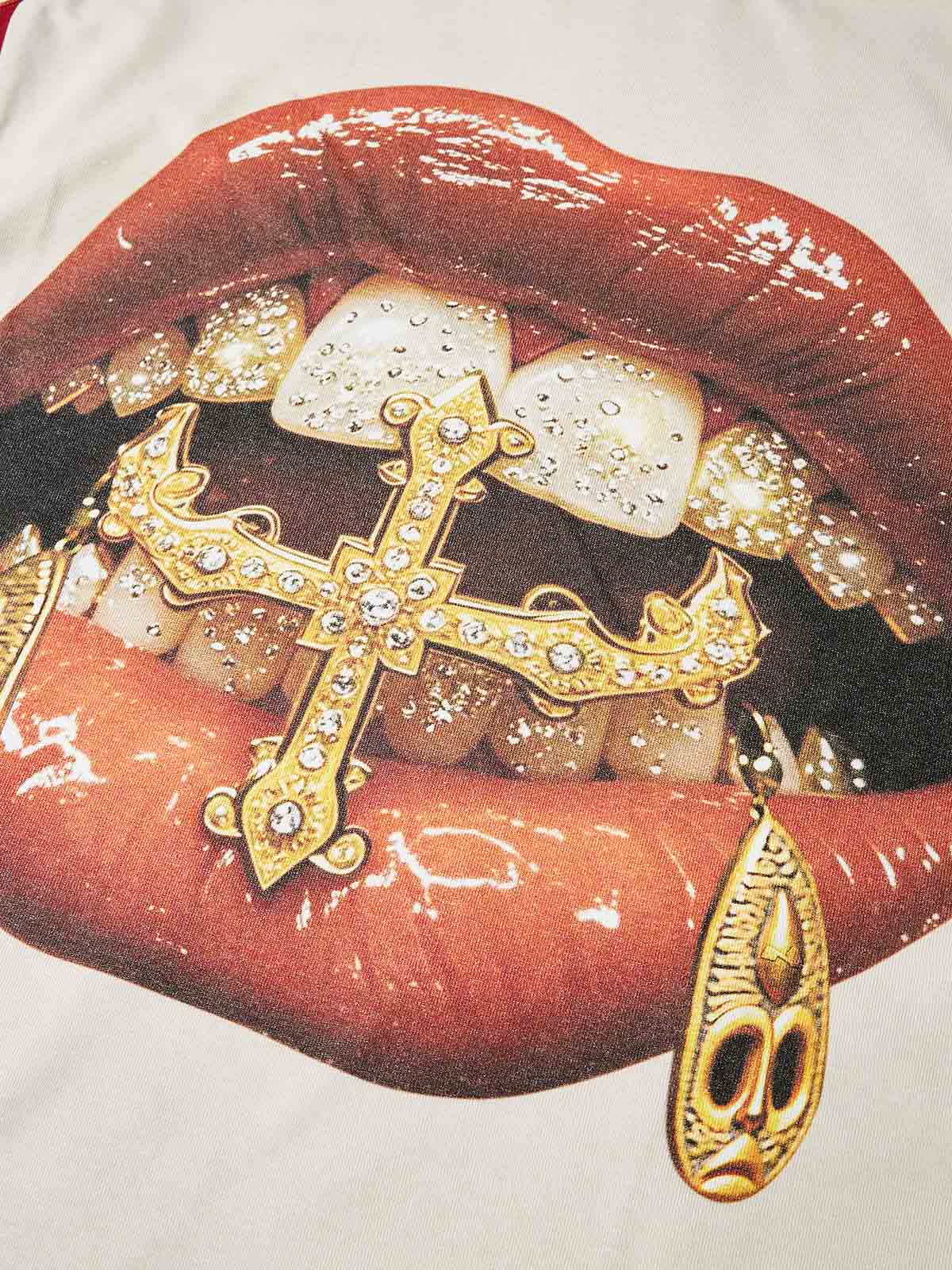 Close-up of lips biting a gold cross grillz pendant with rhinestone effect print