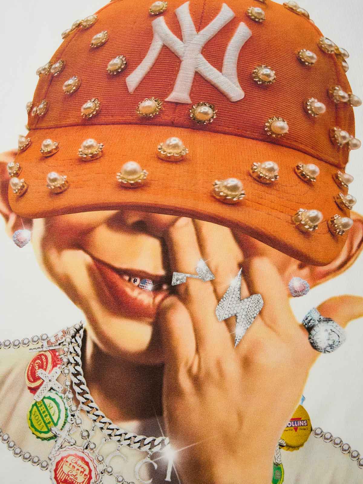 Close-up of mischievous smiling boy wearing orange fuzzy hat with pearls and NY logo