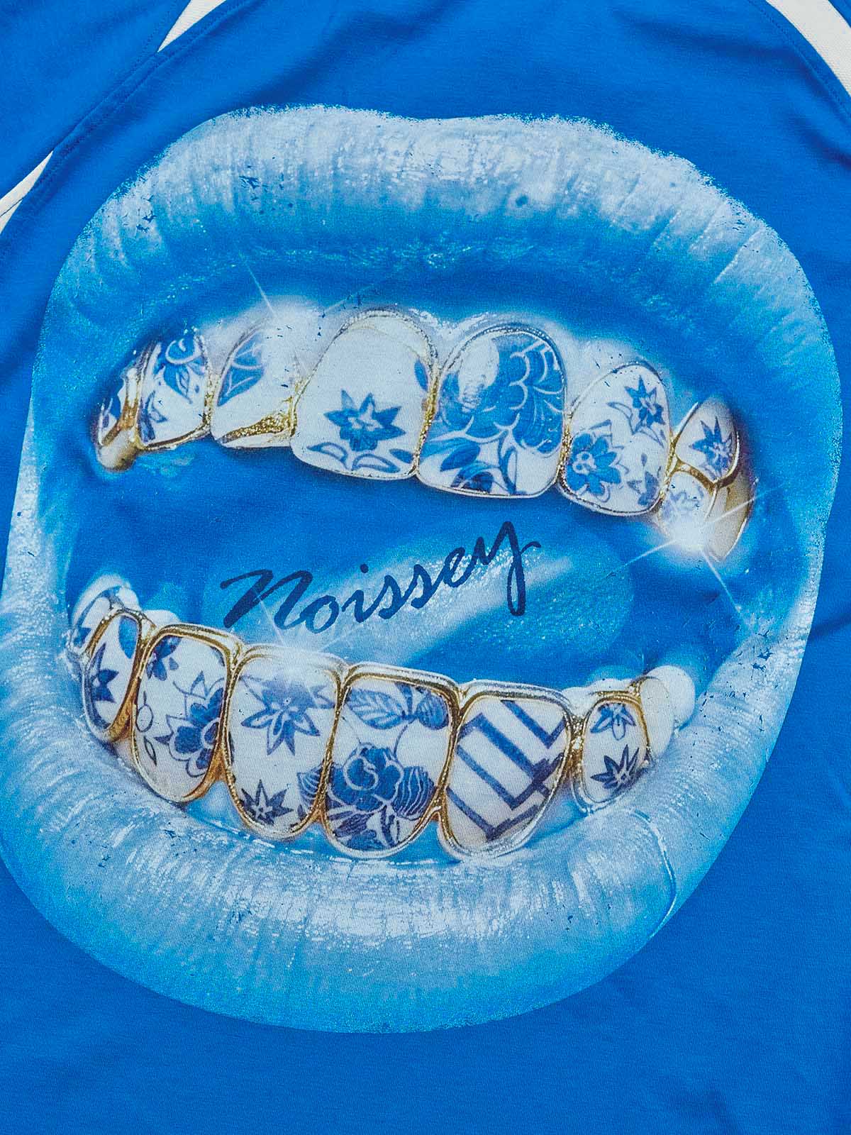 Close-up of the "Porcelain Grillz" print, highlighting the shimmering glitter accents and the intricate floral patterns on the teeth.