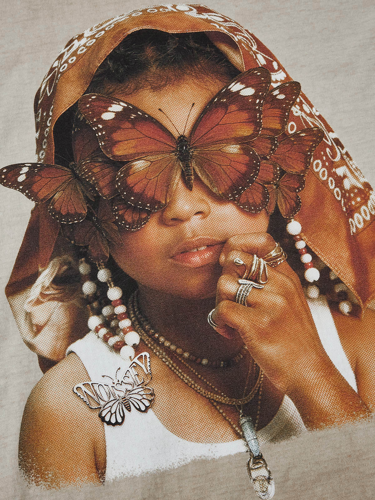 Close-up of the graphic print showing butterflies covering eyes and jewelry details