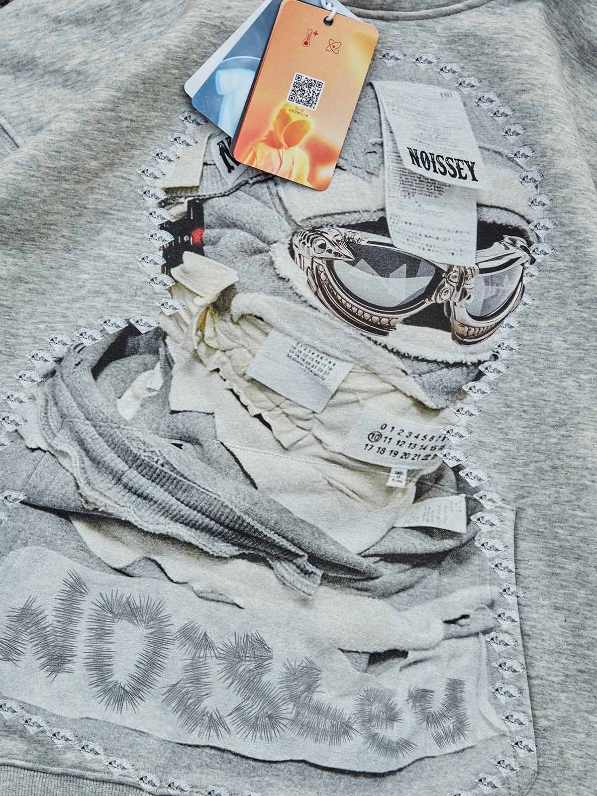 Close-up of the textured masked print and label-inspired artwork on the hoodie's chest.