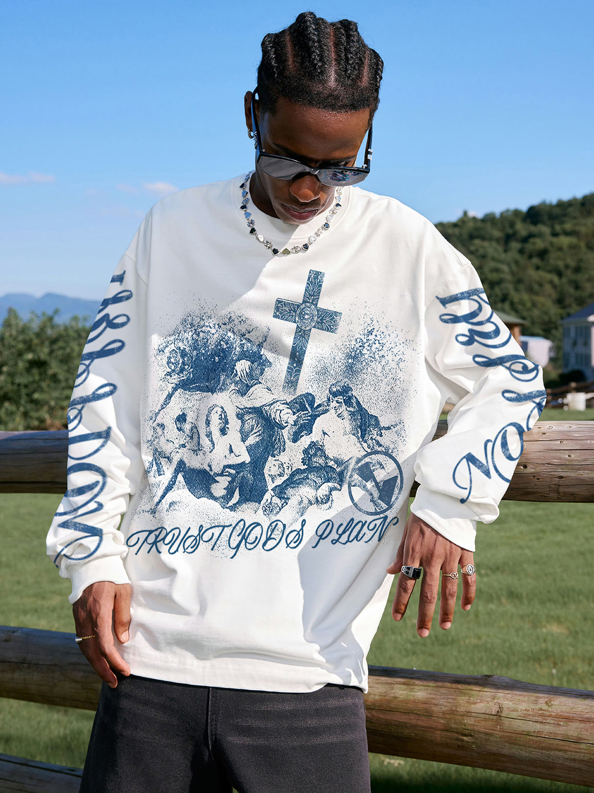 Male model wearing NOISSEY blue religious graphic long sleeve styled with sunglasses