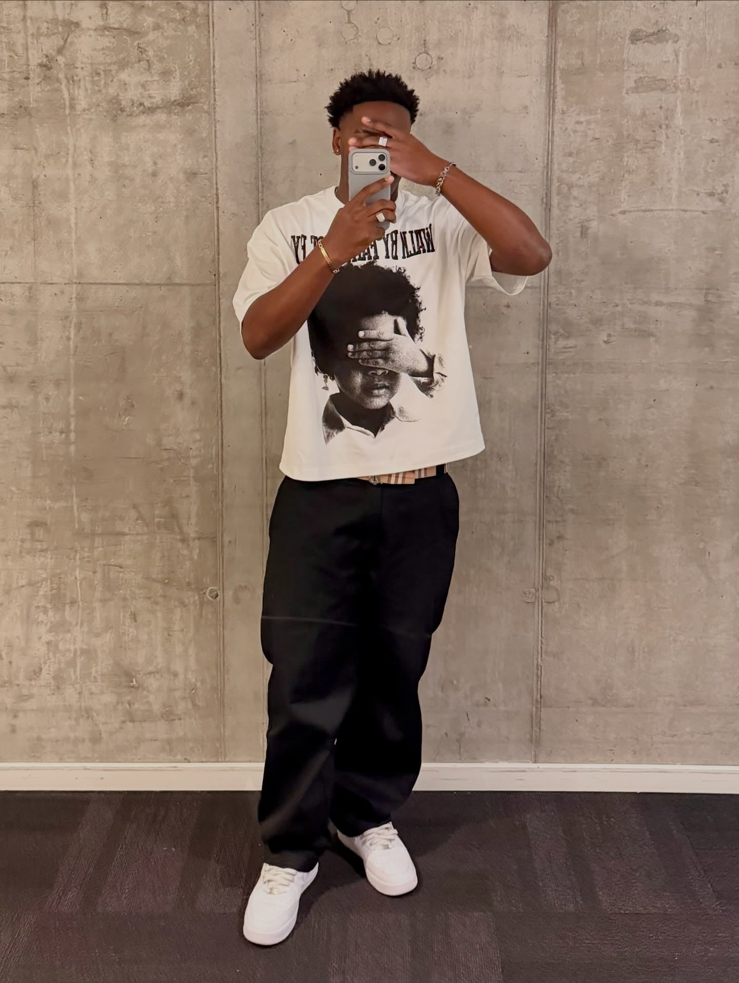 Model wearing the NOISSEY "Walk By Faith" tee styled with dark cargo pants in a street setting