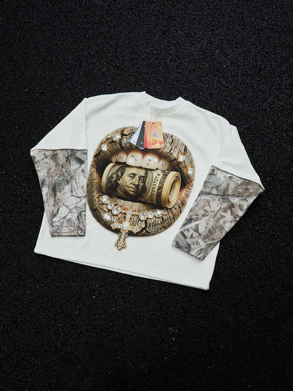 Studio layout of the NOISSEY long sleeve highlighting the contrasting "Real Tree" camouflage printed sleeves and the boxy streetwear silhouette.