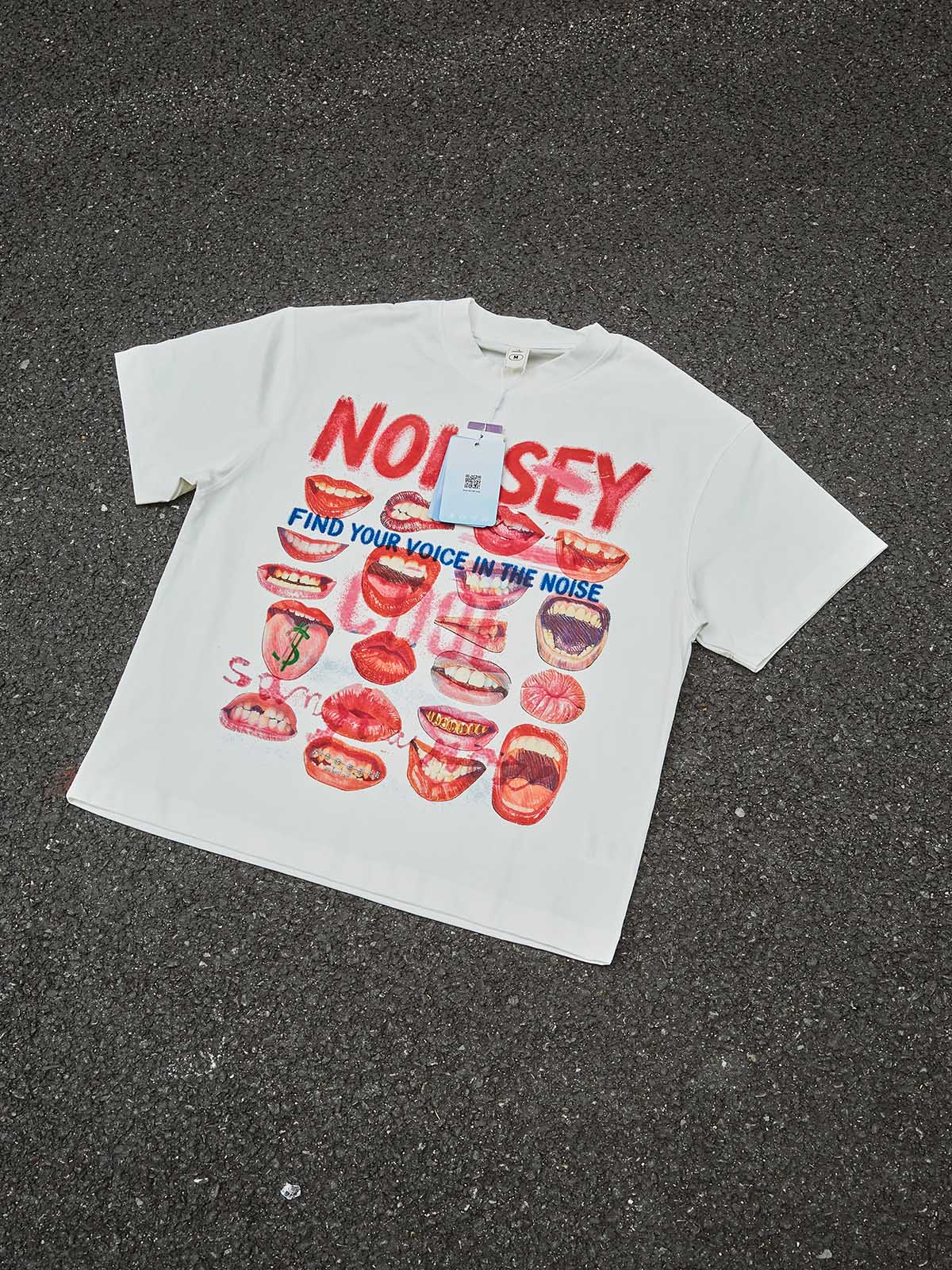 Top-down view of the "Lip Drill" graphic tee with multi-colored mouth prints and bold red NOISSEY branding.